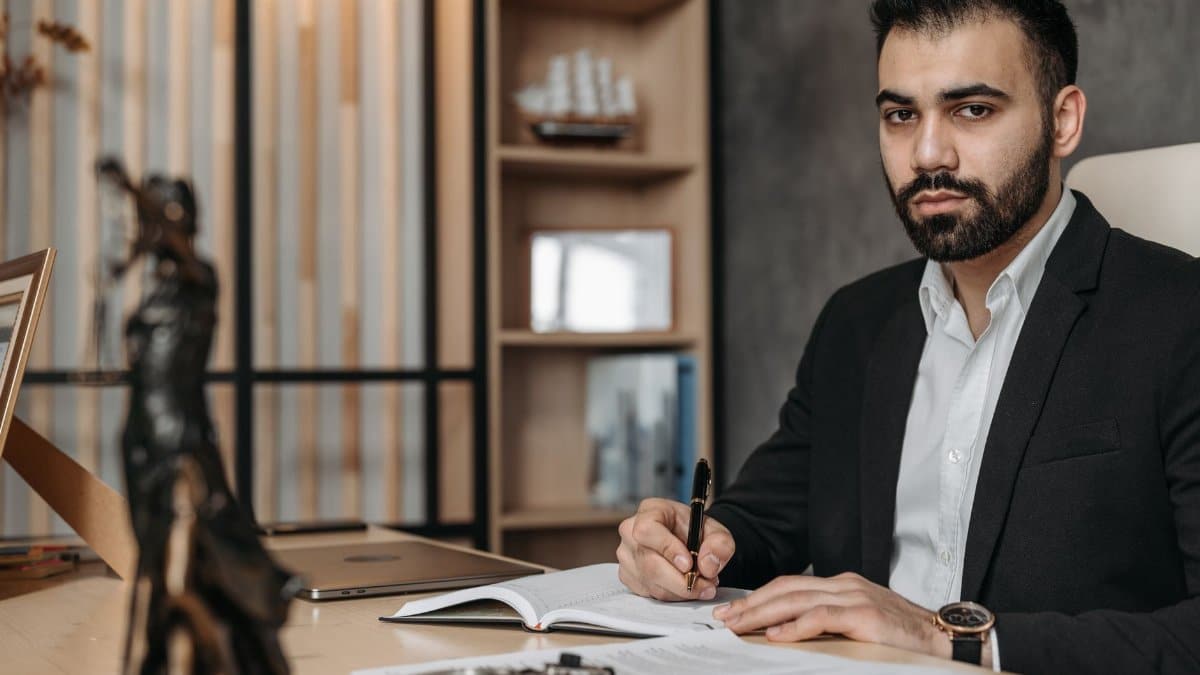 Confident bearded man in an office working on legal documents with a laptop.