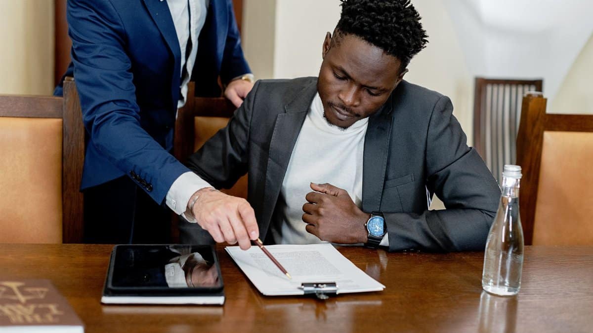 Two businessmen in a legal consultation reviewing a document with a tablet on the desk.