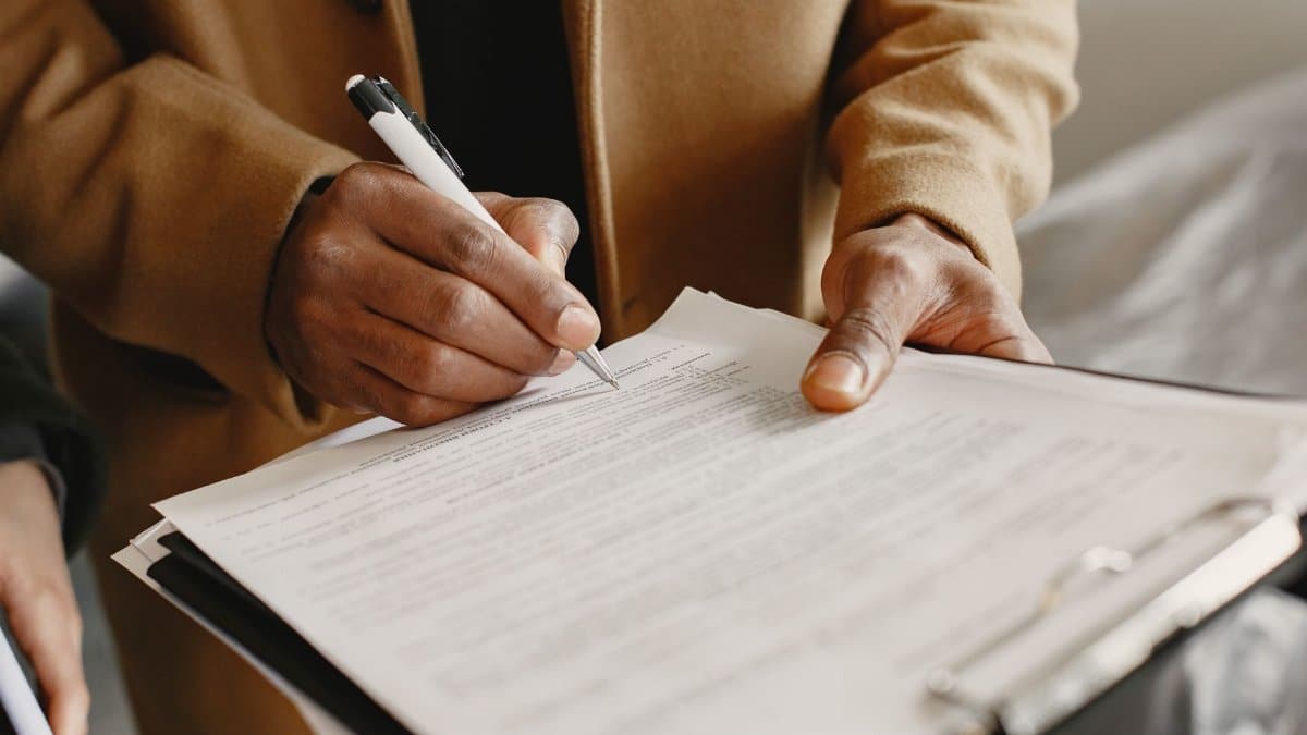 Close-up of a person signing a contract on a clipboard, focusing on legal formalities.