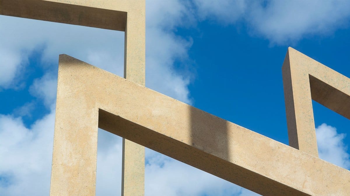 Modern architectural design featuring geometric concrete shapes against a clear blue sky.