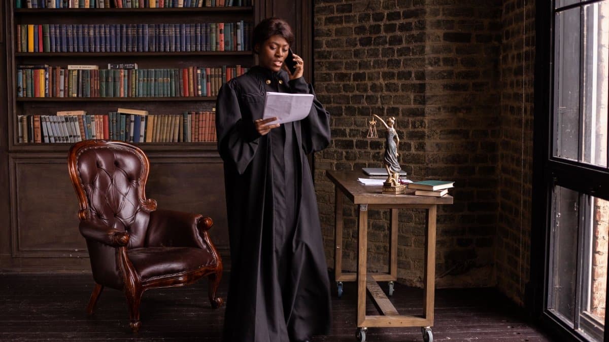 African American female judge talking on phone in a library, reviewing legal documents.