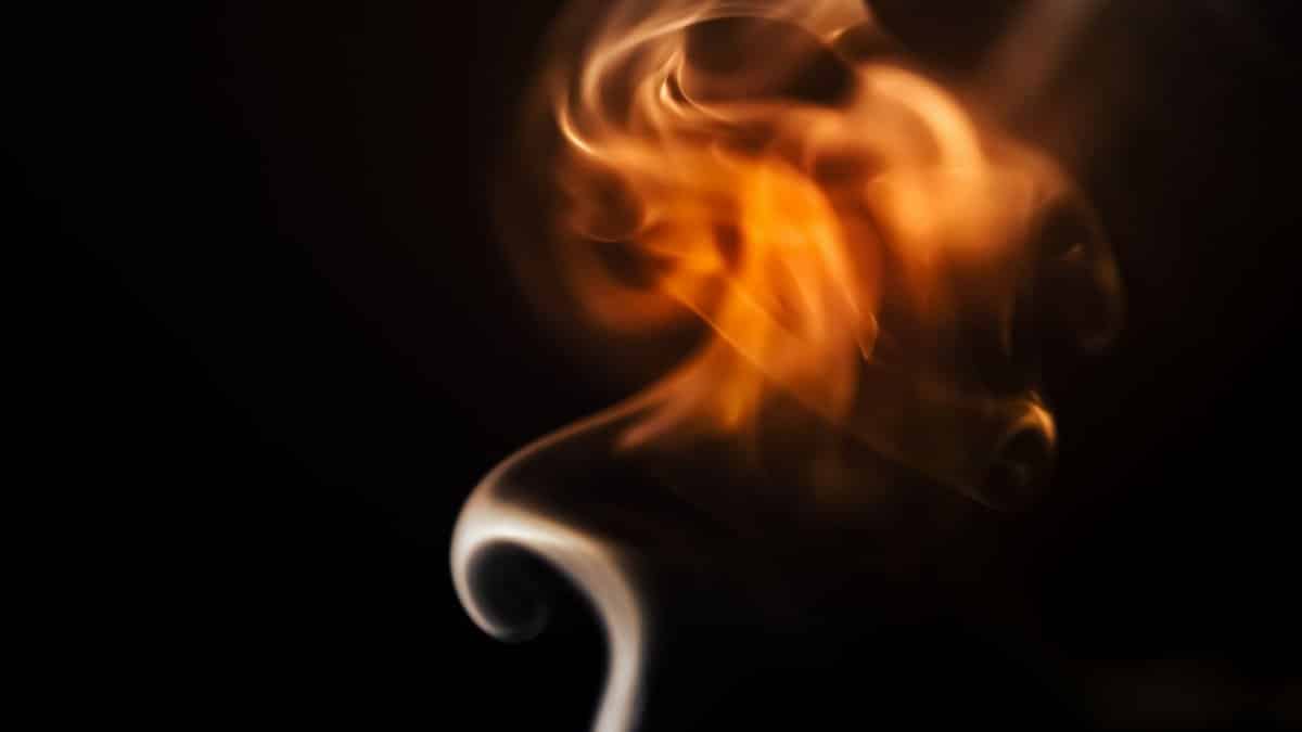 A captivating abstract image of flame and smoke swirling in a dark background, showcasing vibrant colors and fluid movement.