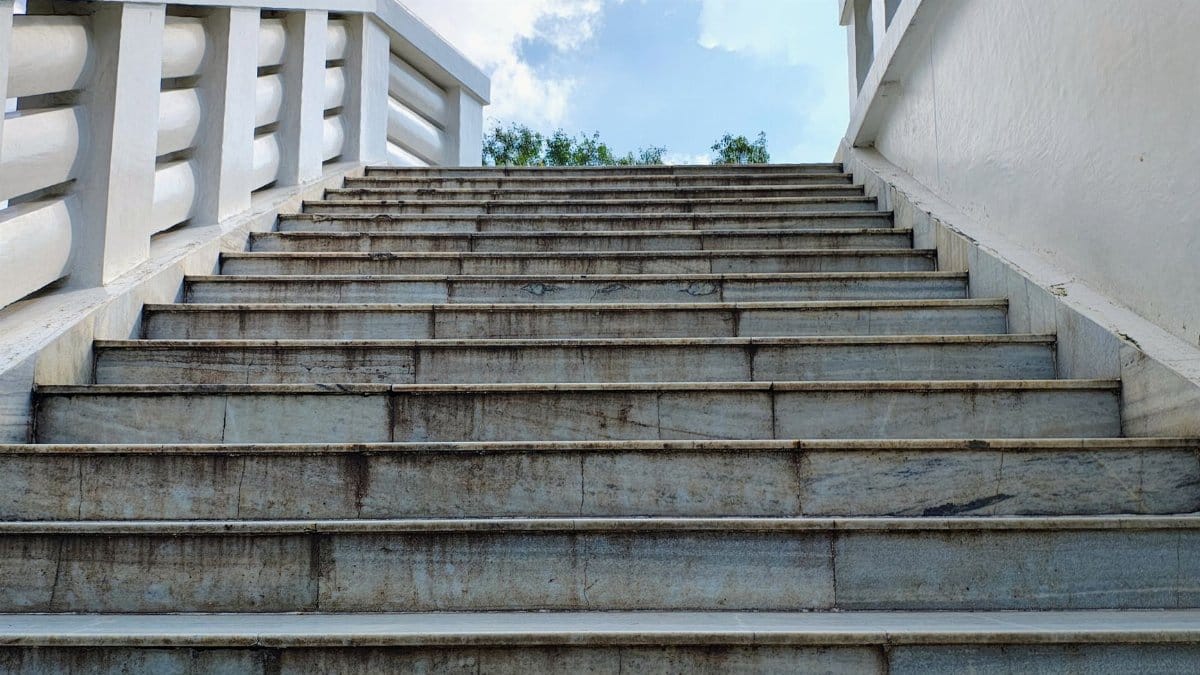 Perspective shot of an outdoor concrete staircase leading up to the sky with white railing.