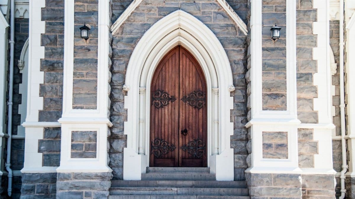 Gothic stone church entrance with ornate wooden arched doors located in South Africa.