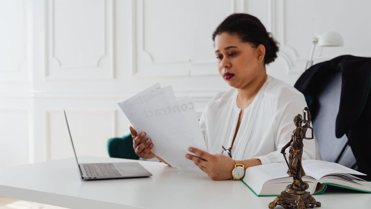 Black woman lawyer reading legal papers at her desk in a modern office.