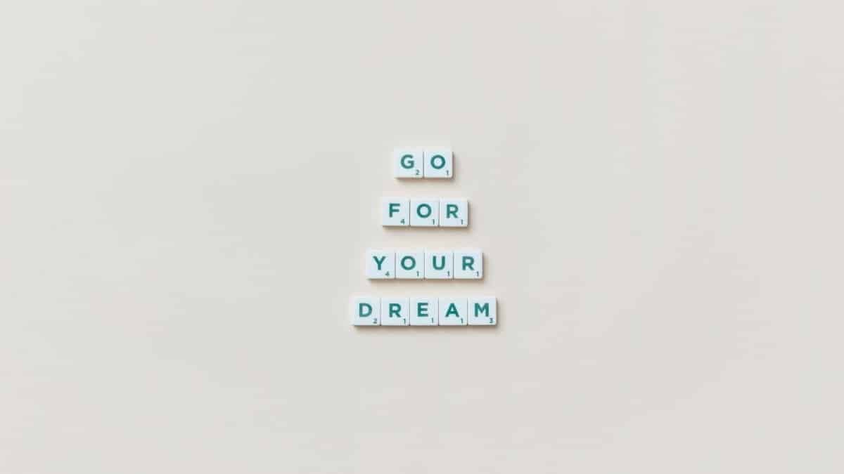 Inspirational text 'Go For Your Dream' made from Scrabble tiles on a plain background.