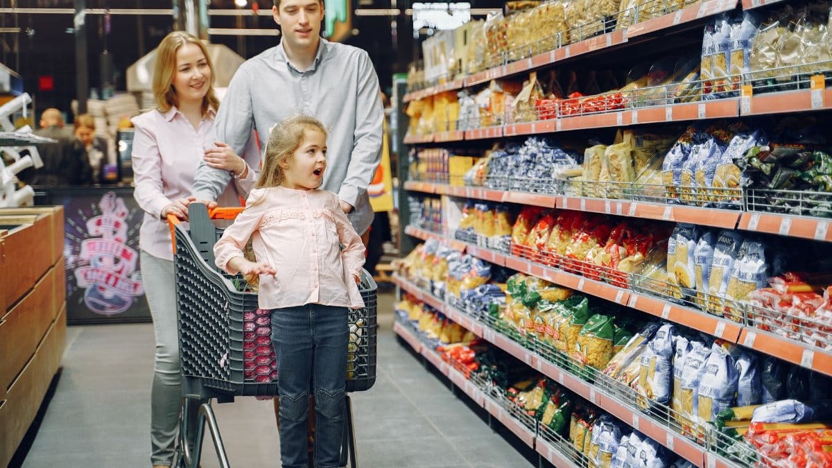 A joyful family enjoying a grocery shopping day together at a supermarket aisle.