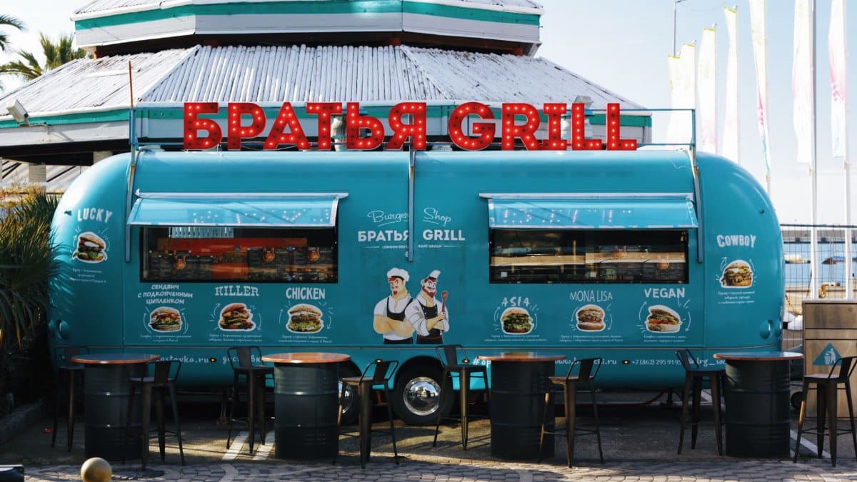 Vibrant blue food truck with Russian signage at a sunny location in Sochi, Russia.