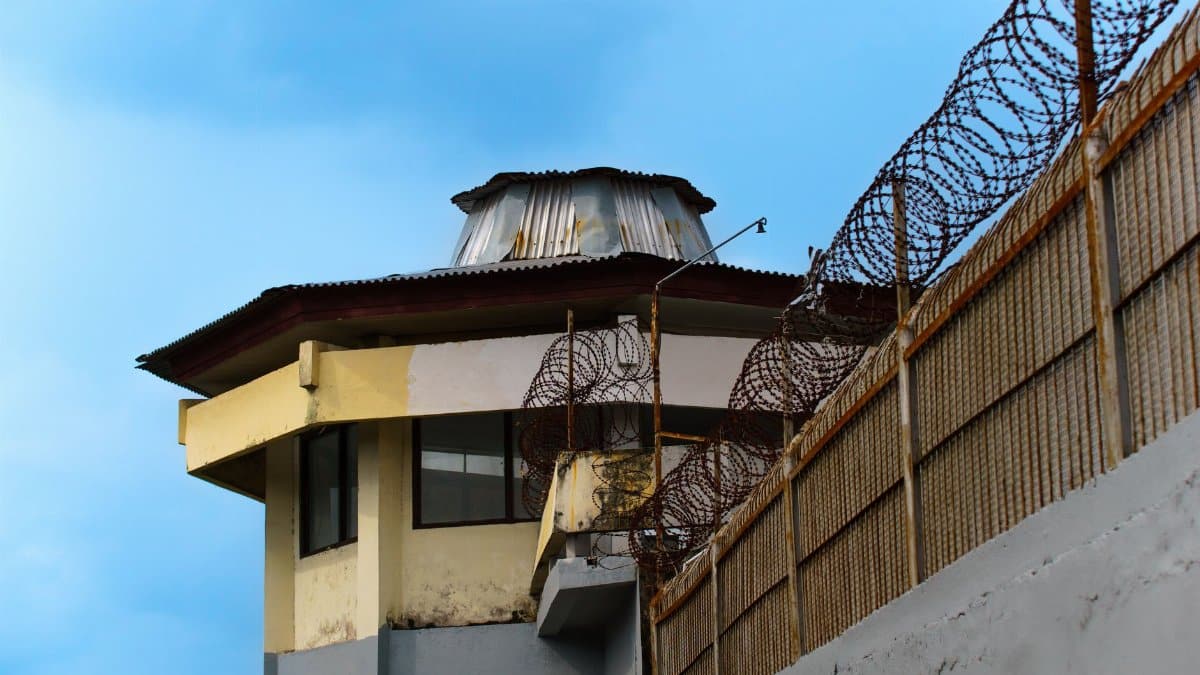 A prison watchtower with barbed wire against a clear blue sky in Bali, Indonesia.