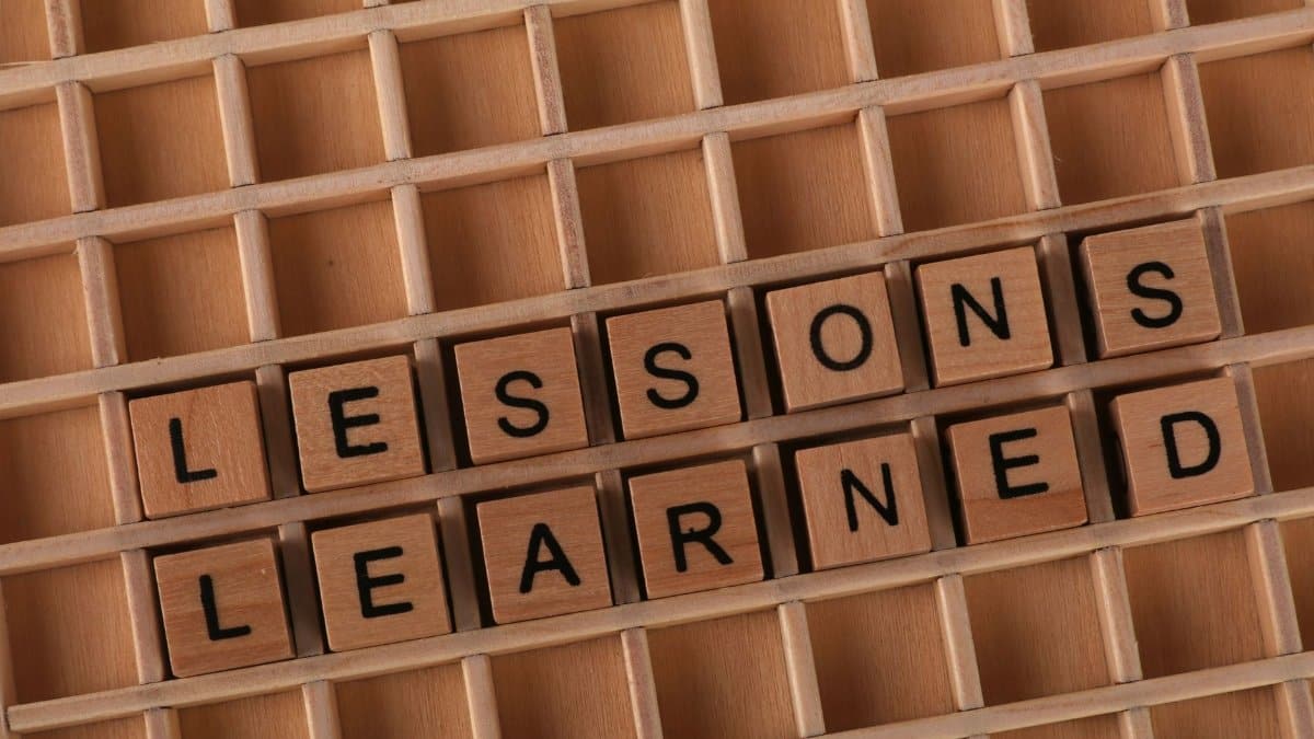 Wooden letter blocks spelling 'lessons learned' on a grid background, symbolizing knowledge and education.