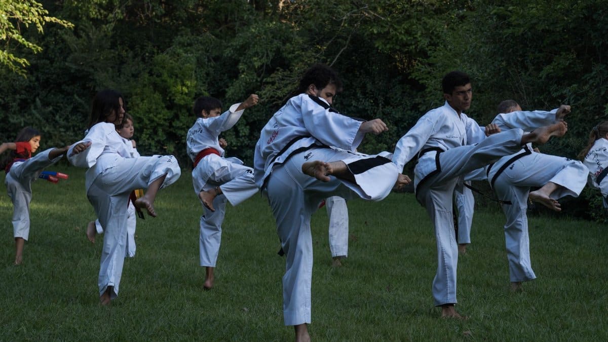 Group of karate students practicing high kicks outdoors in Buenos Aires.