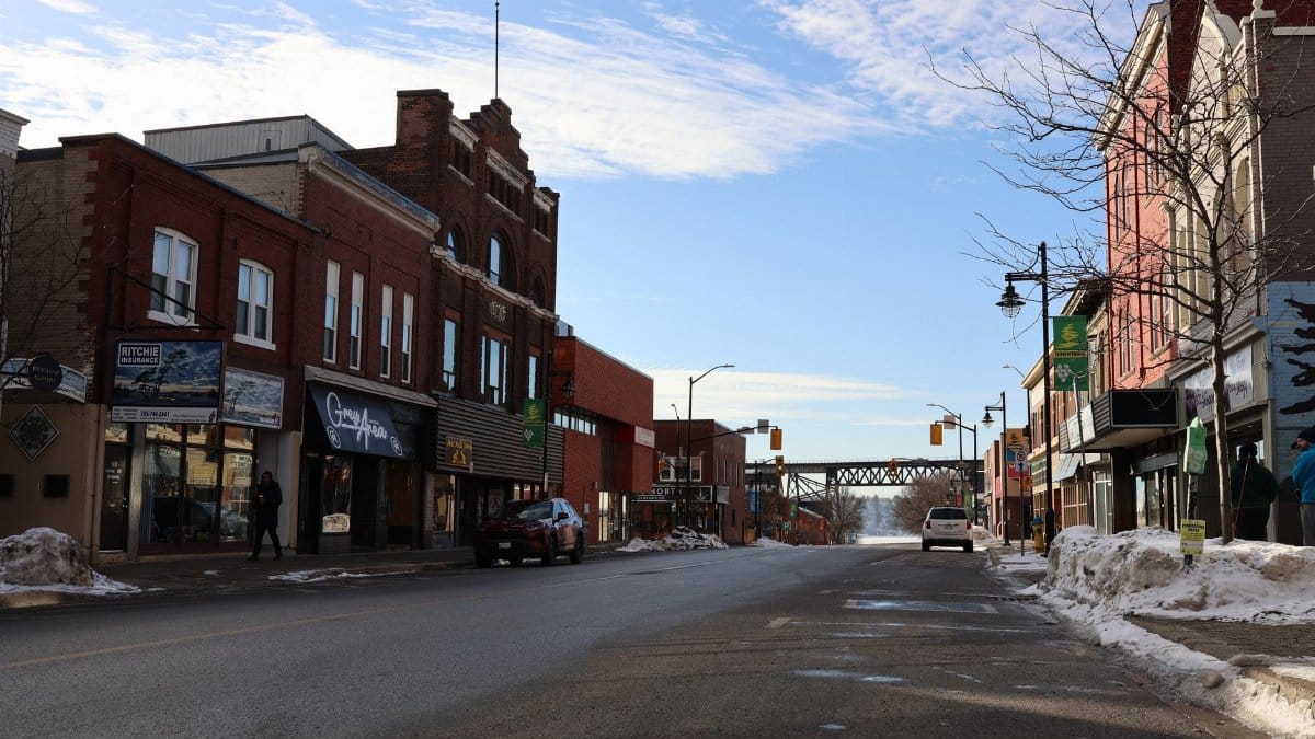 Quaint winter scene of a small town street with historic buildings and a clear blue sky.