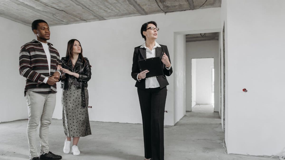 A real estate agent shows an unfinished apartment to prospective buyers.