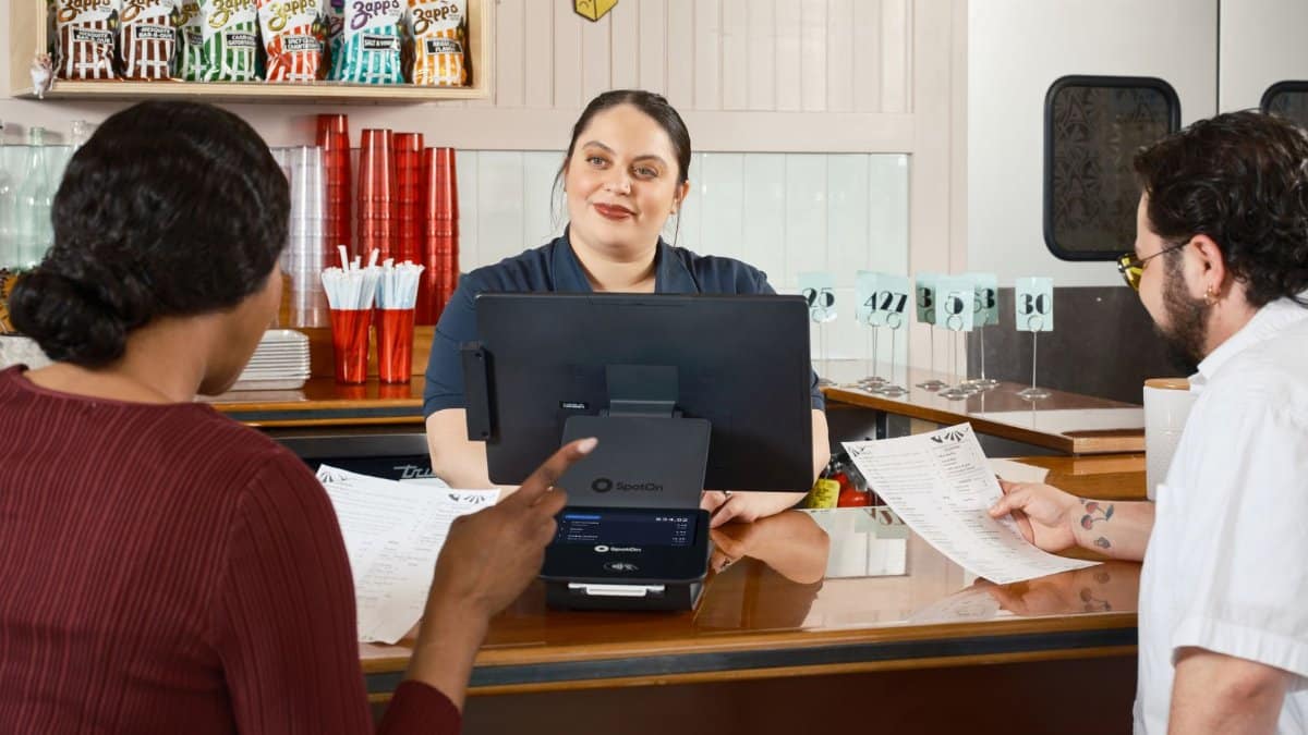 Restaurant staff take orders at a POS system, showcasing modern dining technology.