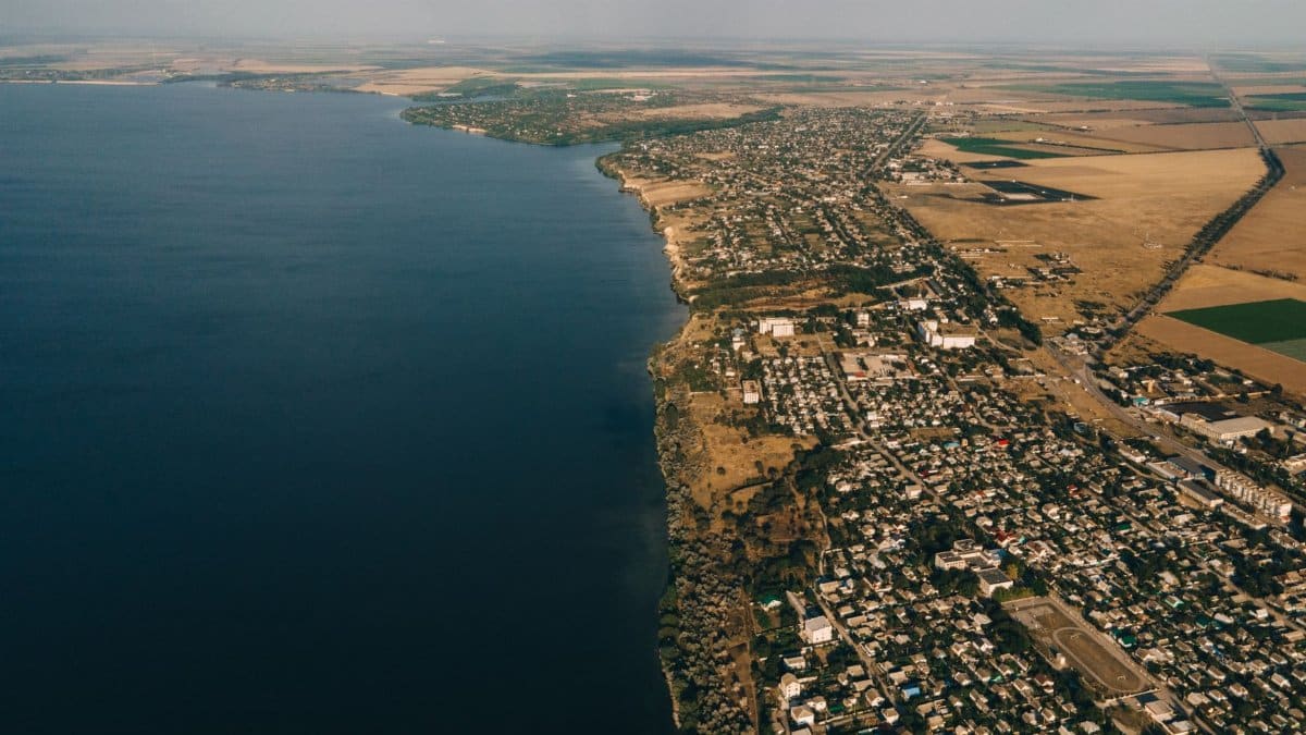 Stunning aerial view of a coastal town beside a vast body of water, showcasing diverse landscapes.