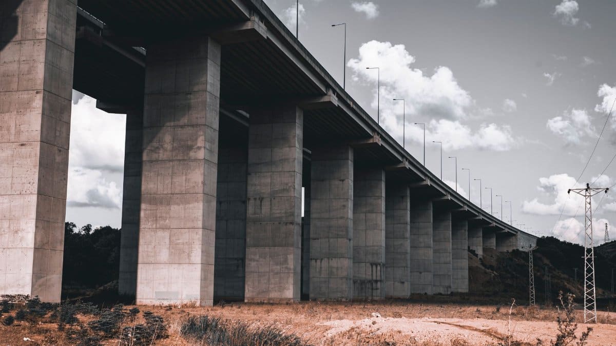 A striking view of a concrete bridge with columns stretching towards a cloudy sky.