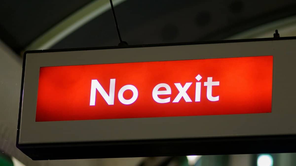 Brightly lit 'No Exit' sign in an indoor subway station setting.