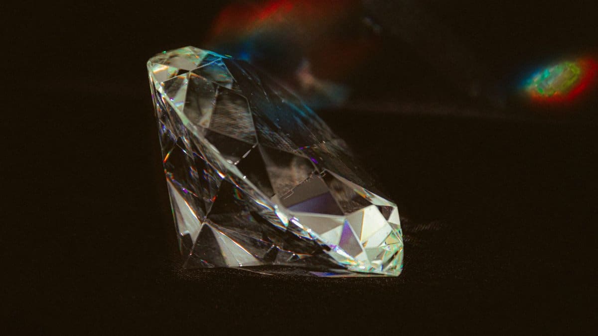 Stunning close-up of a diamond gem with prismatic reflections on a dark surface.