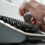 Detailed shot of hands typing on an antique typewriter, showcasing vintage technology.