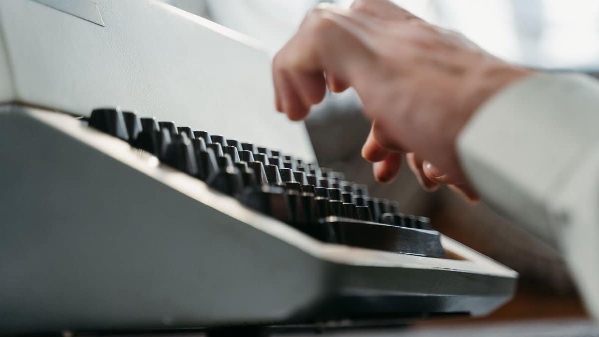 Detailed shot of hands typing on an antique typewriter, showcasing vintage technology.