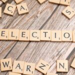 Wooden letter tiles form the word 'election' on a textured wooden surface, symbolizing voting.