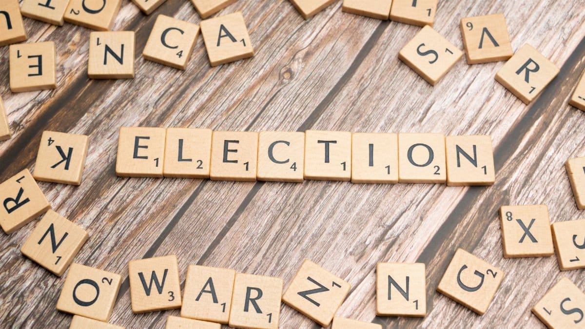 Wooden letter tiles form the word 'election' on a textured wooden surface, symbolizing voting.