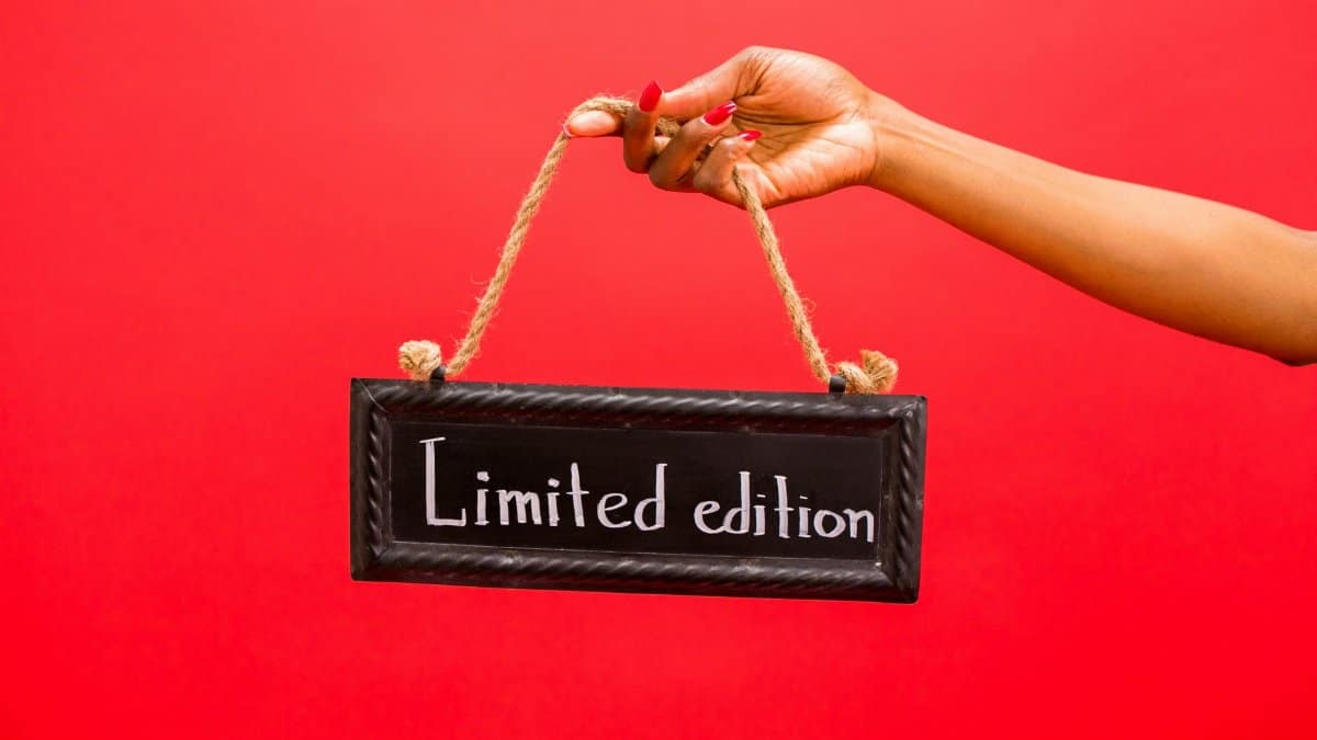 A hand holds a limited edition sign against a vibrant red background, perfect for marketing use.