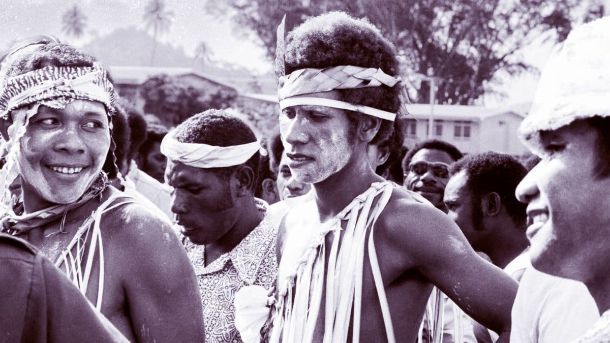 A group of indigenous people in traditional attire during an outdoor ceremony, exhibiting cultural heritage.