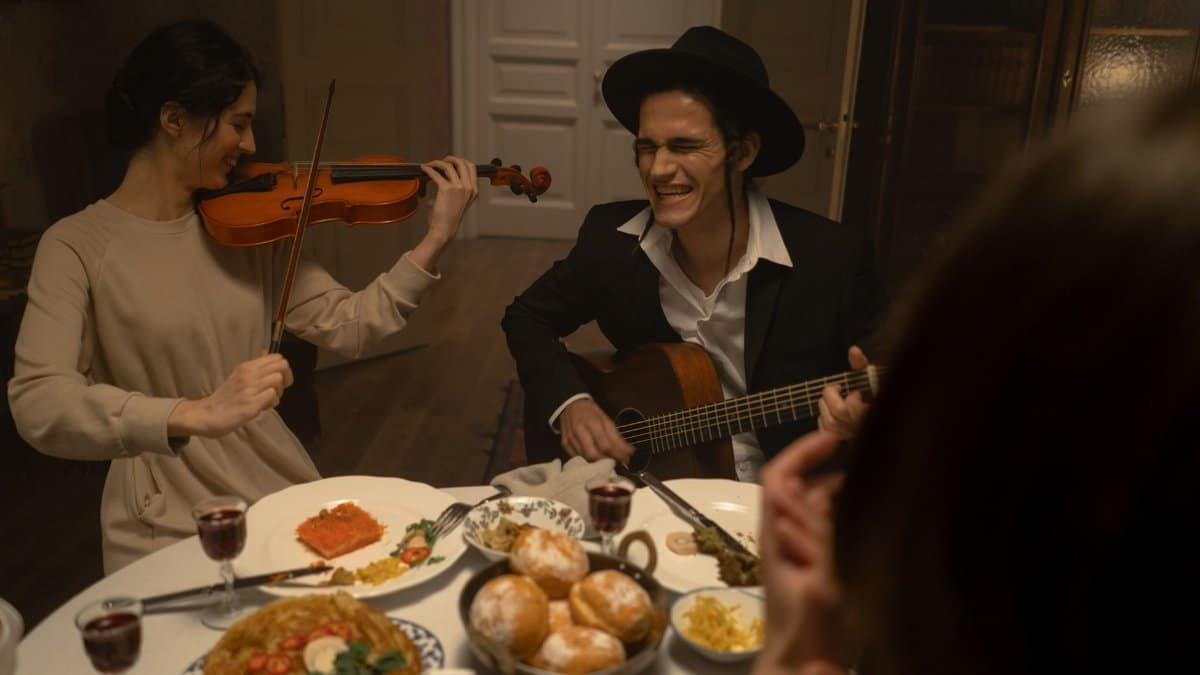 A joyful Hanukkah dinner with family enjoying music and traditional foods indoors.