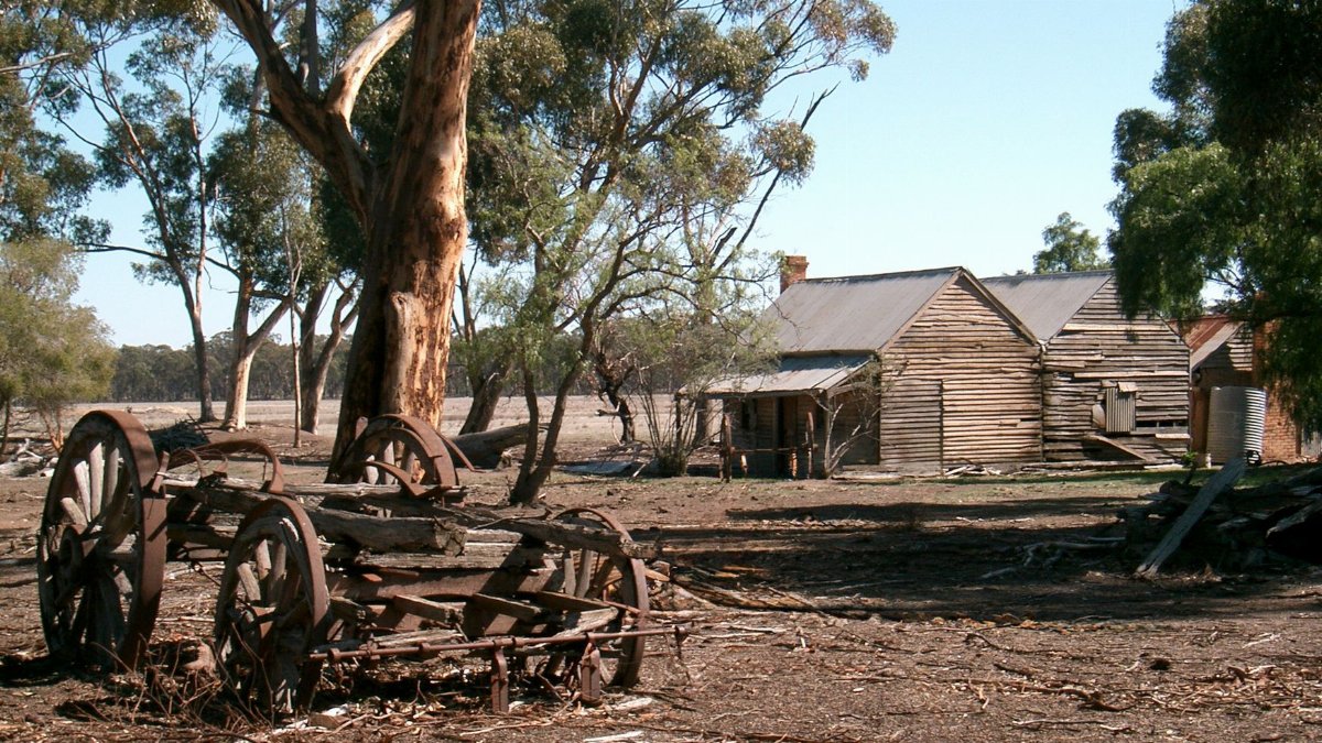 Old farm buildings and rusted equipment on a sunny day in Rushworth, Victoria, Australia.