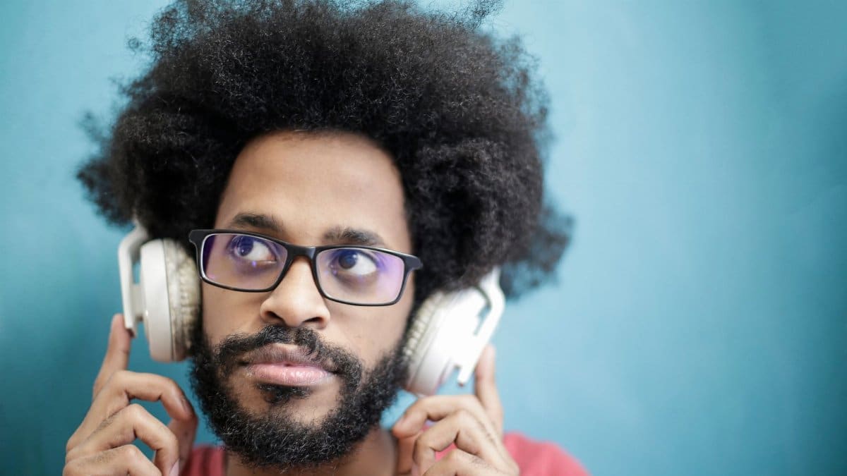Portrait of a man with afro hairstyle enjoying music with headphones. Vibrant and stylish.