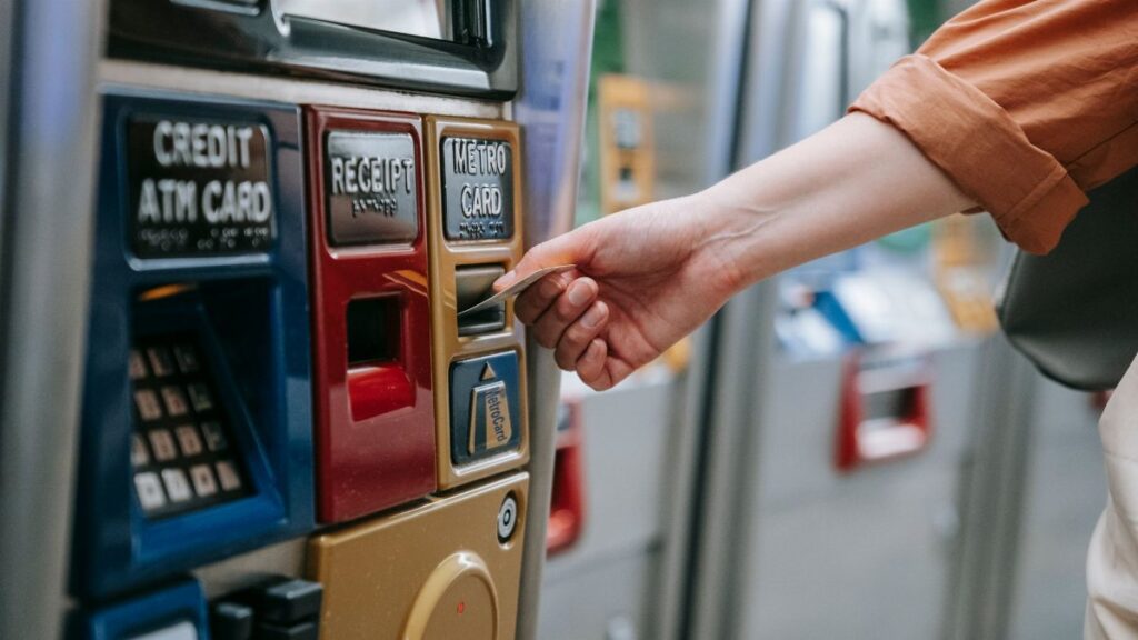 Close-up of a person using a metro card machine for public transport payment indoors.