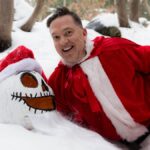 Man dressed as Santa with a snowman in a snowy forest in Owen Sound, Ontario.