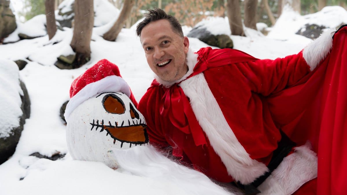 Man dressed as Santa with a snowman in a snowy forest in Owen Sound, Ontario.