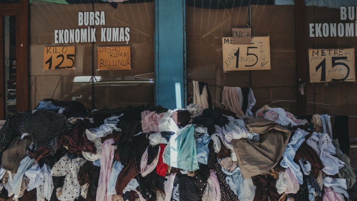 A textile shop in Bursa with a colorful pile of fabrics displayed outside, offering economic prices.