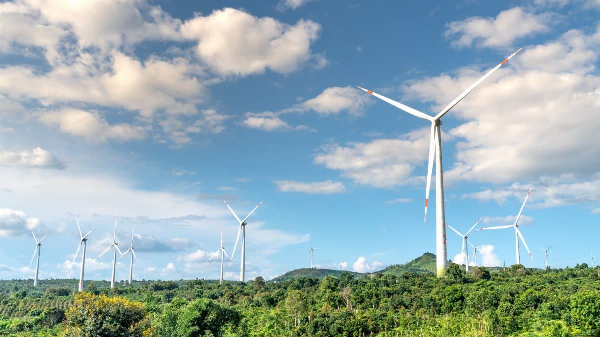 Wind turbines in a lush green field with a dramatic cloudy sky, illustrating renewable energy.
