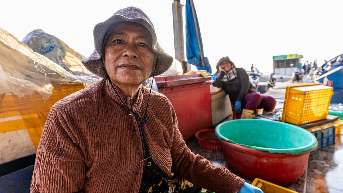 Portrait of a woman at an outdoor fish market, showcasing the vibrant life of local vendors.