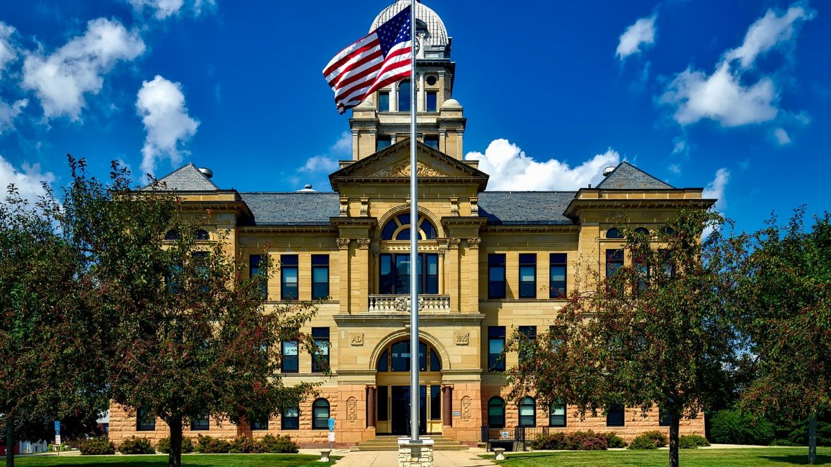 Grand courthouse in Cedar Rapids with an American flag in a bright blue sky.