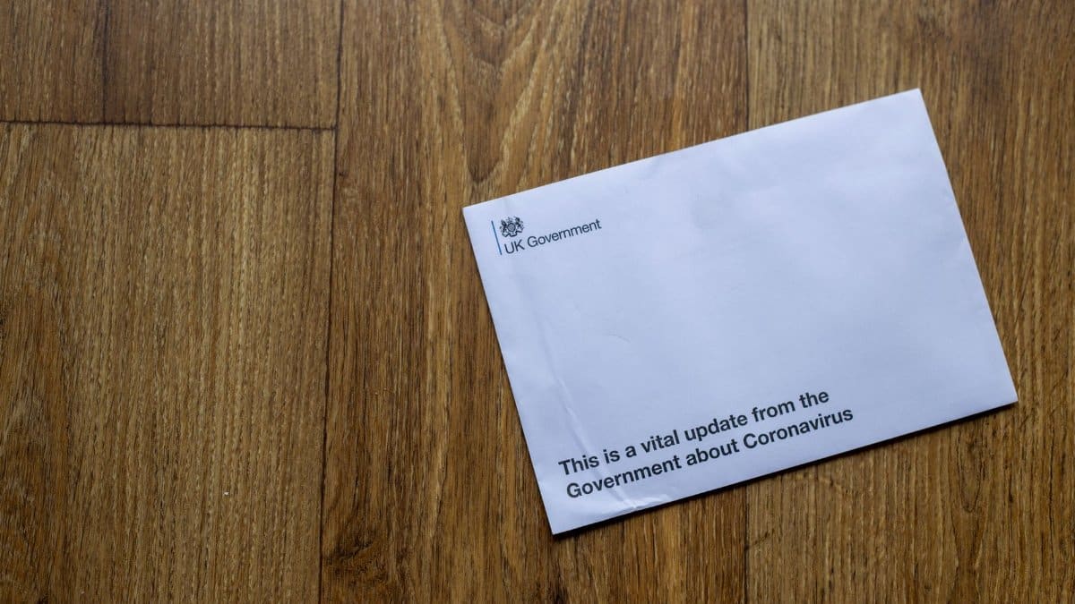 A UK Government envelope with coronavirus update on a wooden floor.
