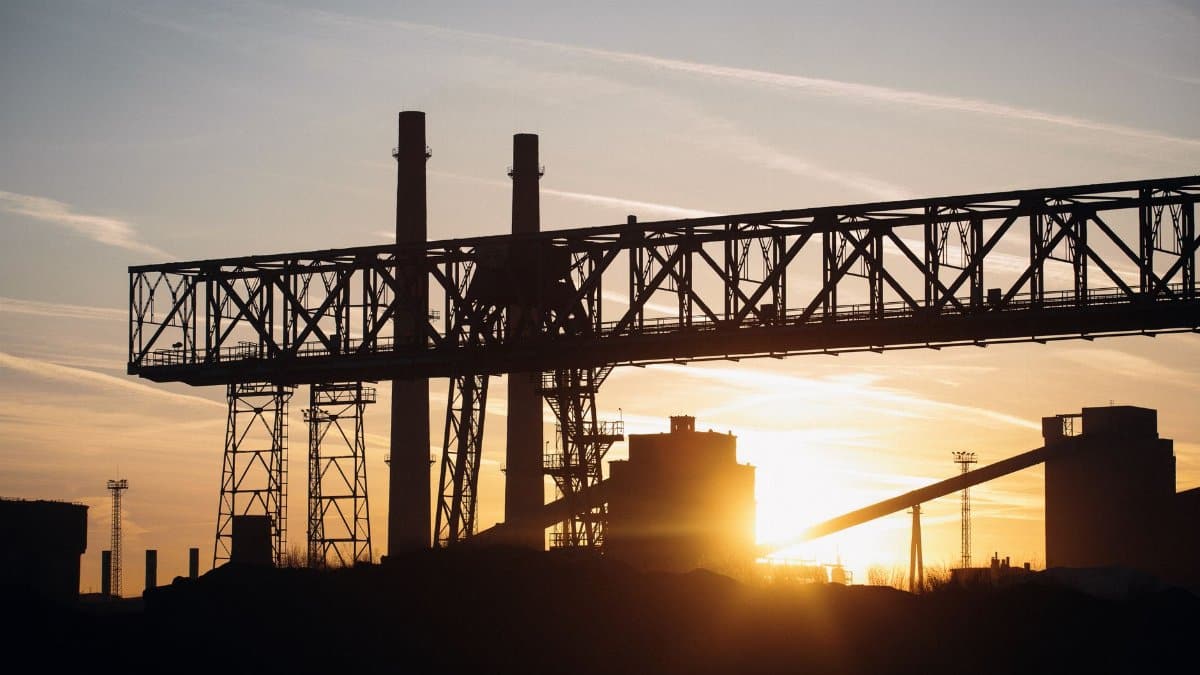 Silhouette of an industrial structure against a sunset sky, symbolizing industry and energy.