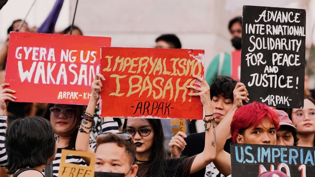 Demonstrators at a protest holding signs against imperialism and solidarity for justice.