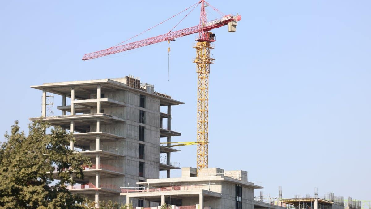 Concrete high-rise building under construction with a tower crane in Uzbekistan.