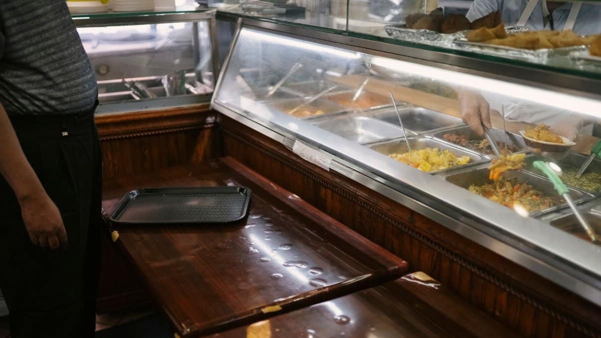 Crop unrecognizable person with tray choosing and buying meal for dinner in canteen
