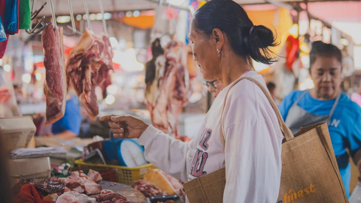 A woman selecting fresh meat at a vibrant local market, highlighting traditional shopping experiences.