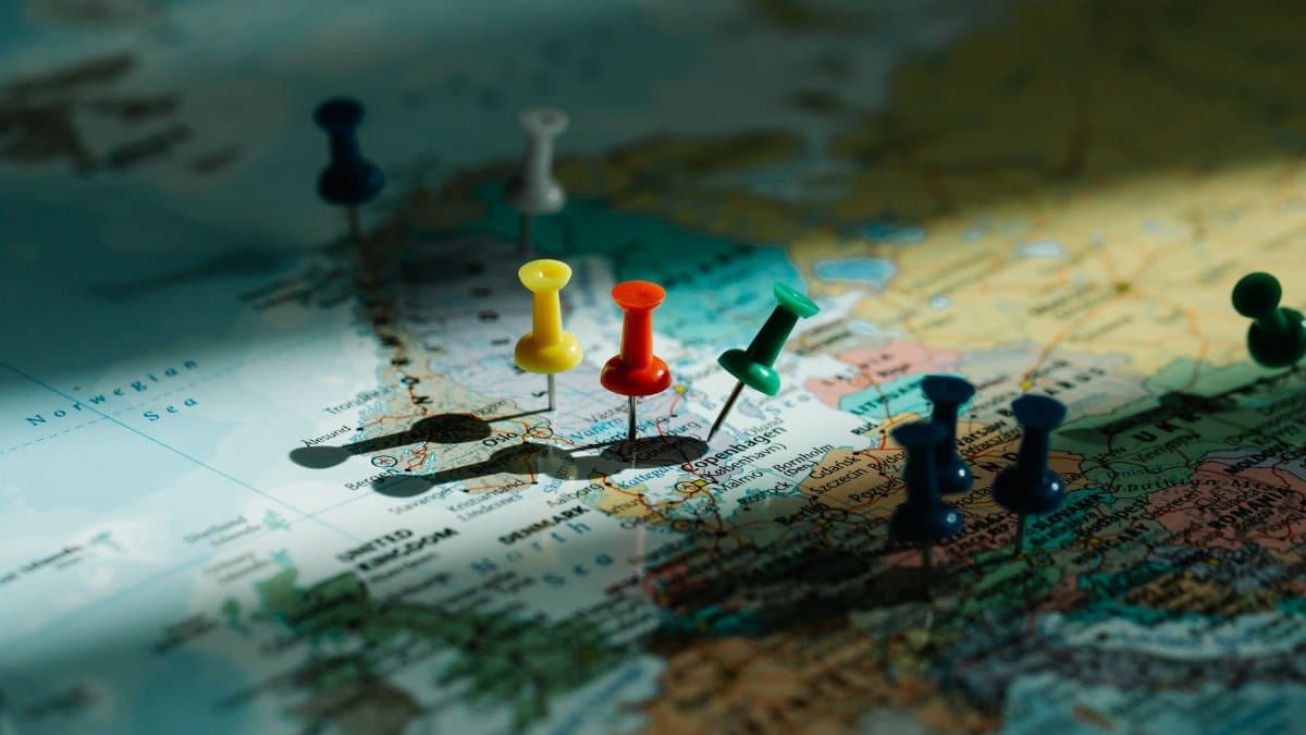 A close-up view of colorful push pins marking locations on a detailed world map.