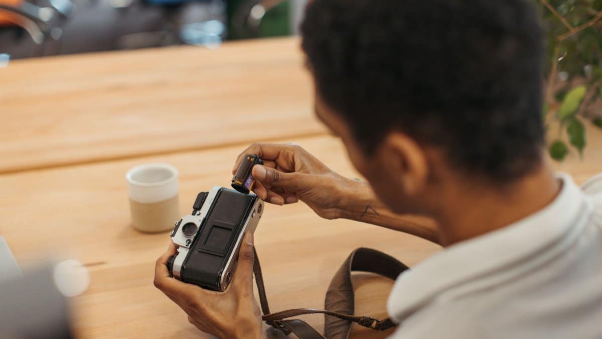 Person loading a roll of film into a vintage camera, focused with hands visible.