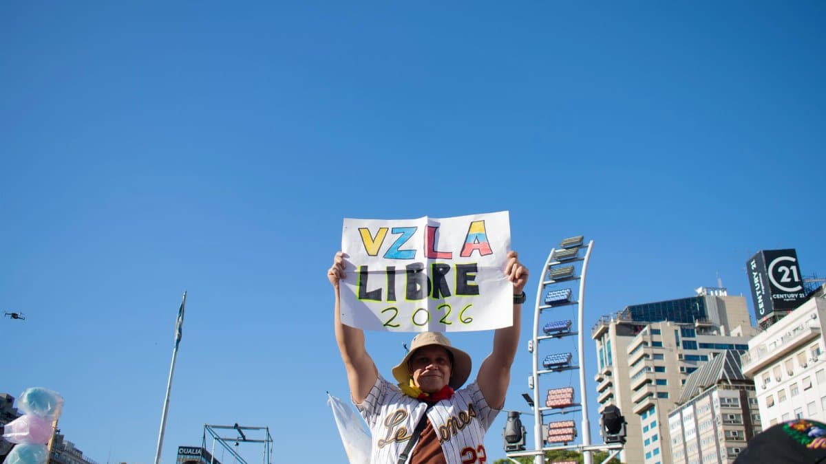 A person holds a sign reading 'VZLA Libre 2026' in a peaceful protest with a city backdrop.
