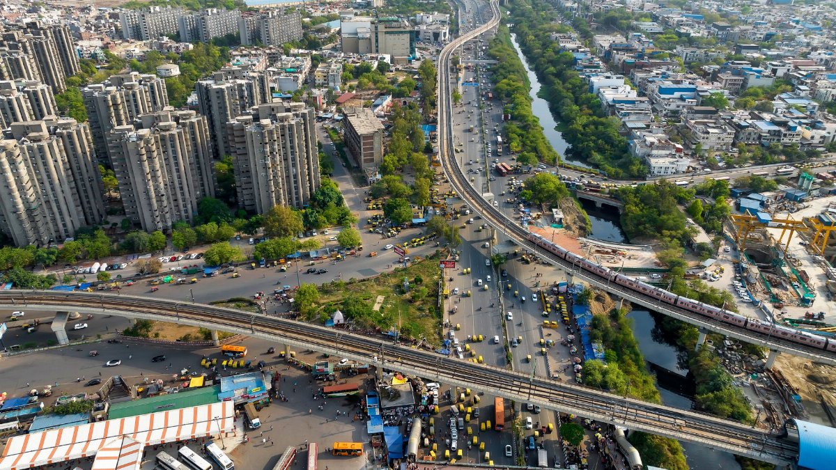 Dynamic aerial view of urban cityscape showing highways, buildings, and greenery.
