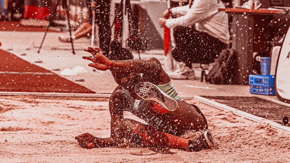 Athlete landing in sand during a long jump competition, showcasing athleticism and motion.