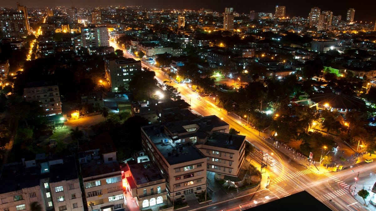 Aerial view of a bustling city at night with vibrant light trails and illuminated skyscrapers.